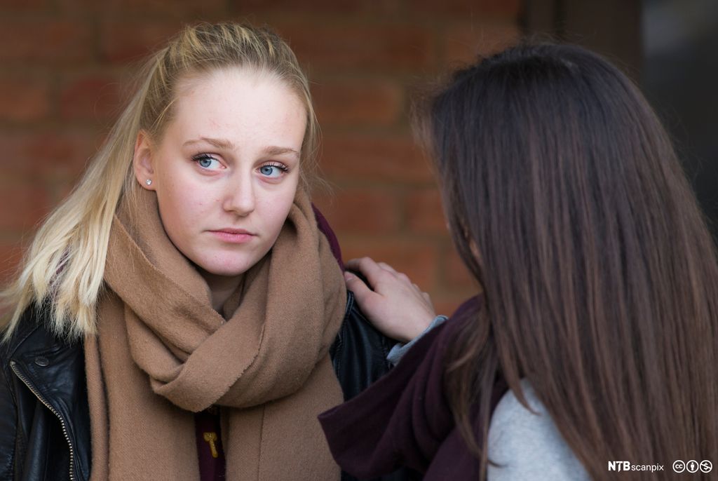 To unge jenter snakker fortrolig sammen. Foto.