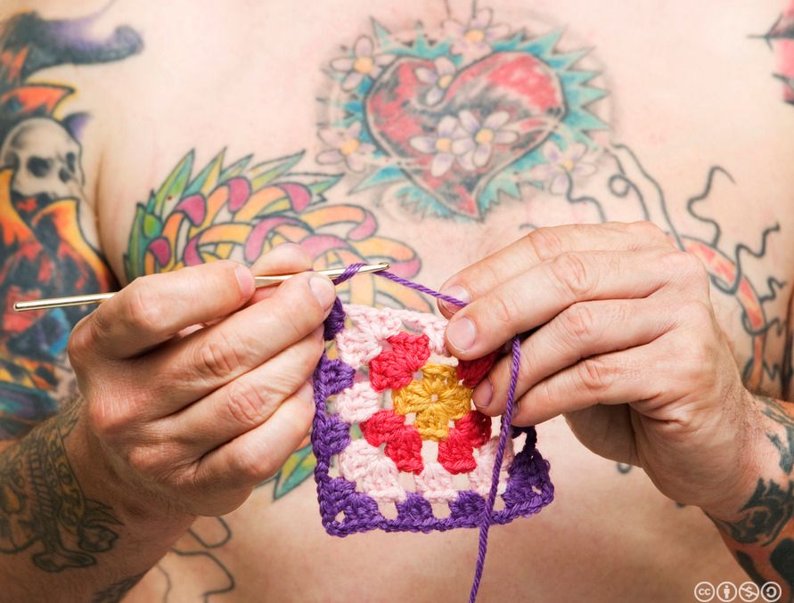 Mann med tatovering heklar. Foto.