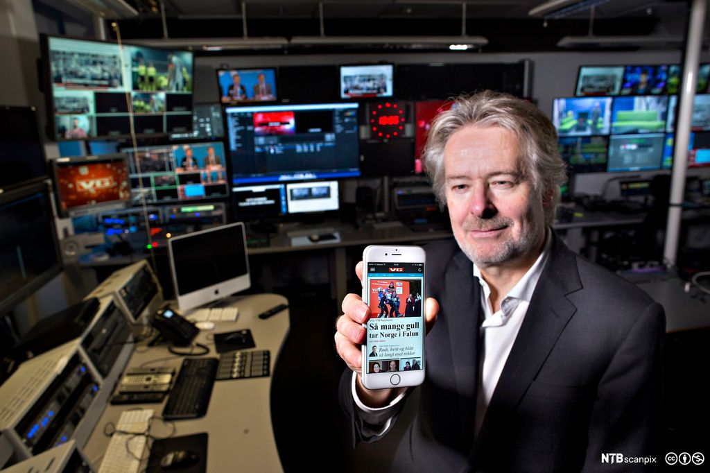 Redaktør Torry Pedersen holder opp en mobil med VGs nettsider i VGs fjernsynsstudio. Foto.