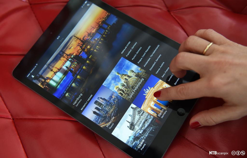 Ei nettside med ulike bilder av reisemål er åpnet på et nettbrett. En person trykker på bildet med tittelen "Berlin". Foto.