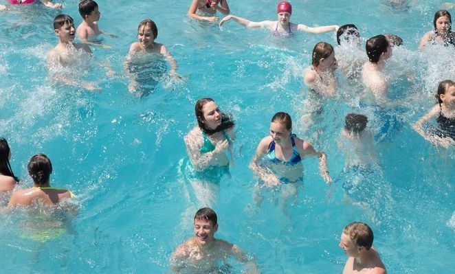 Foto av et stort antall unge mennesker som bader i et utendørs badeanlegg i Tyskland.