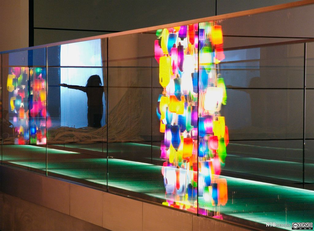 Refleksjoner av fargede flasker og jente i speil. Foto.