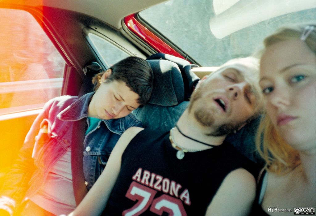 Tre ungdommer i baksete på en bil. Foto.