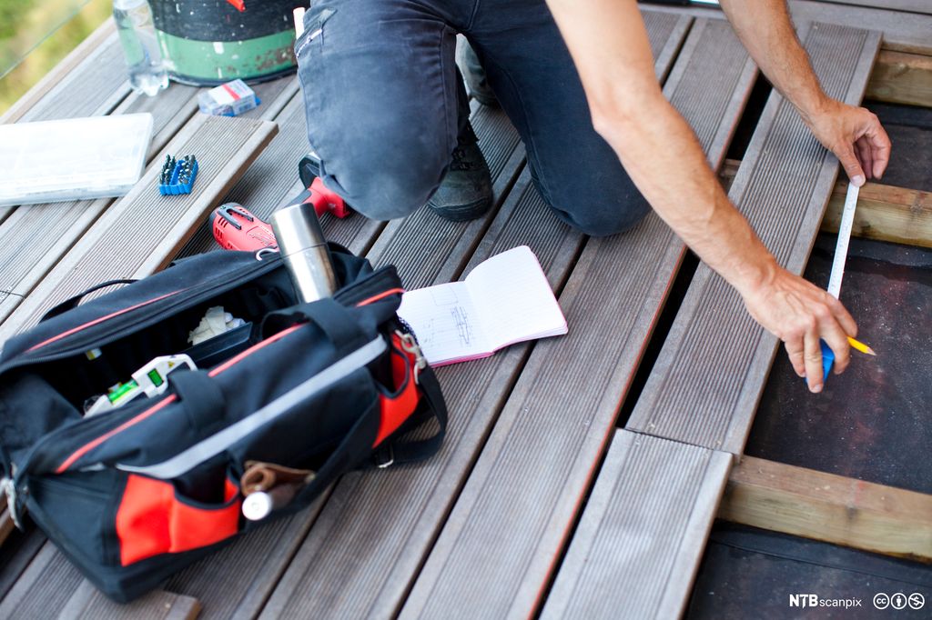 Snekker som legger gulv på terrasse. Foto.