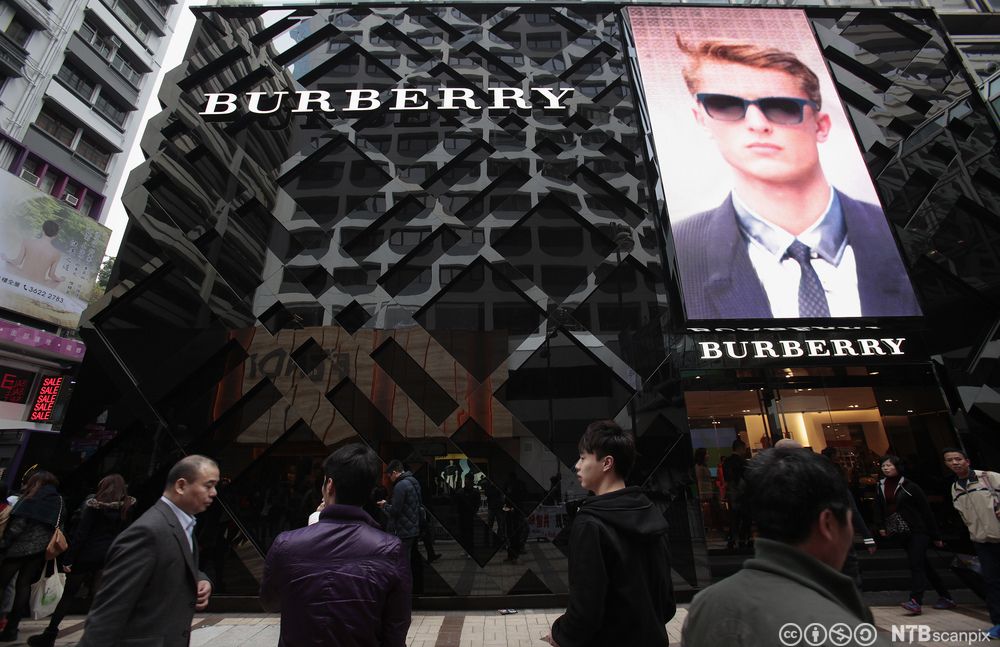 Folk passerer utenfor en Burberry butikk i Hong Kong. Foto.