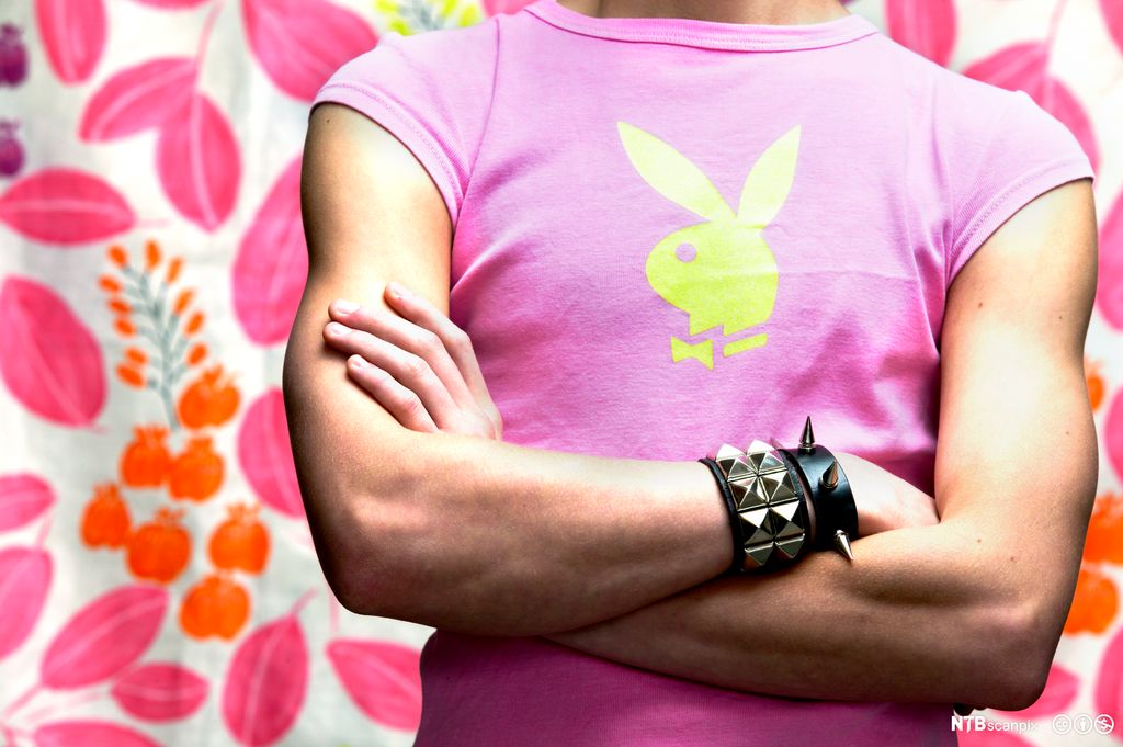 Person med rosa t-skjorte og svart lærarmband med piggar. Foto.