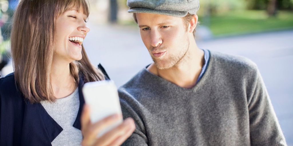 Par som ser på mobiltelefon. Foto.