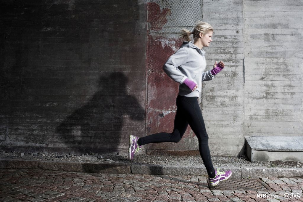 Kvinne jogger på gata. Foto.
