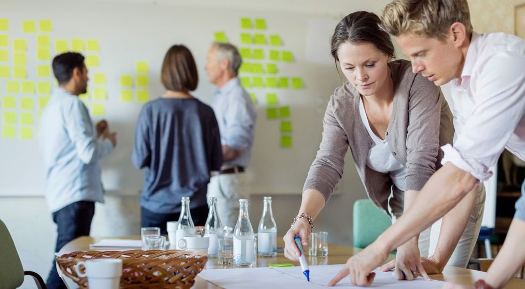 Forretningsfolk diskuterer over tegning på konferansebordet. Bilde.