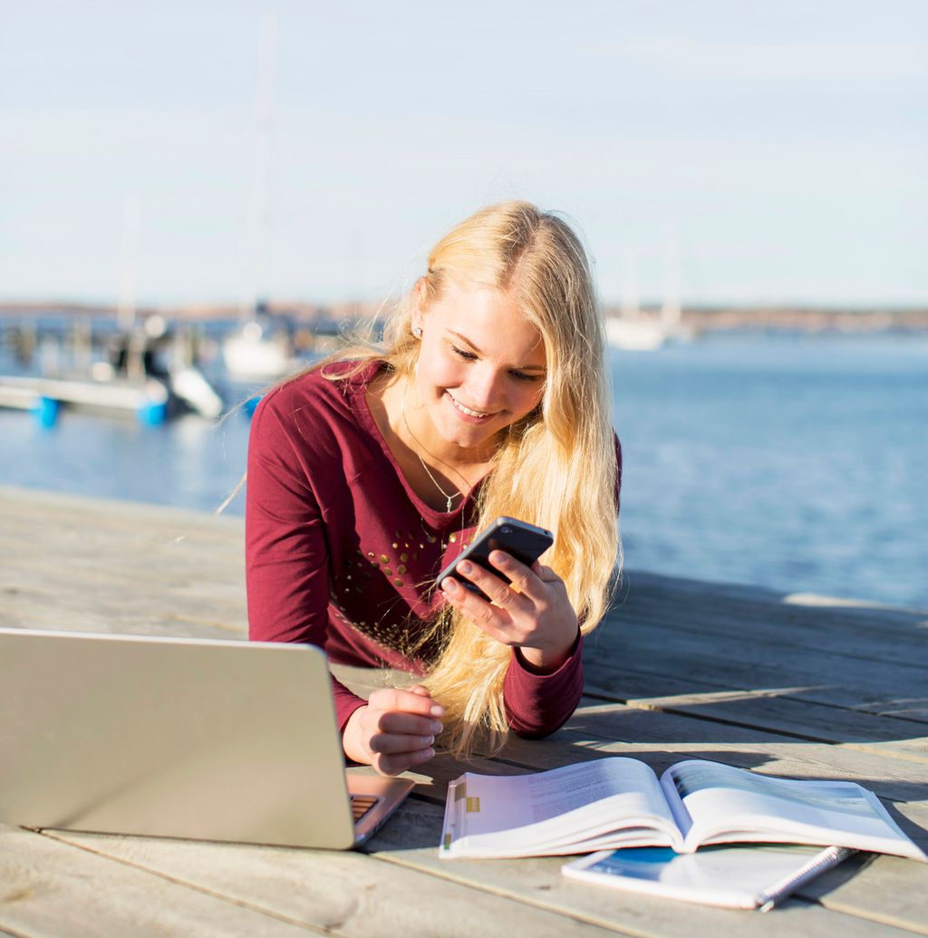 Nieida veallá čoavjji alde ja geahččá mátketelefovnna, dihtora ja girjji. Govva.