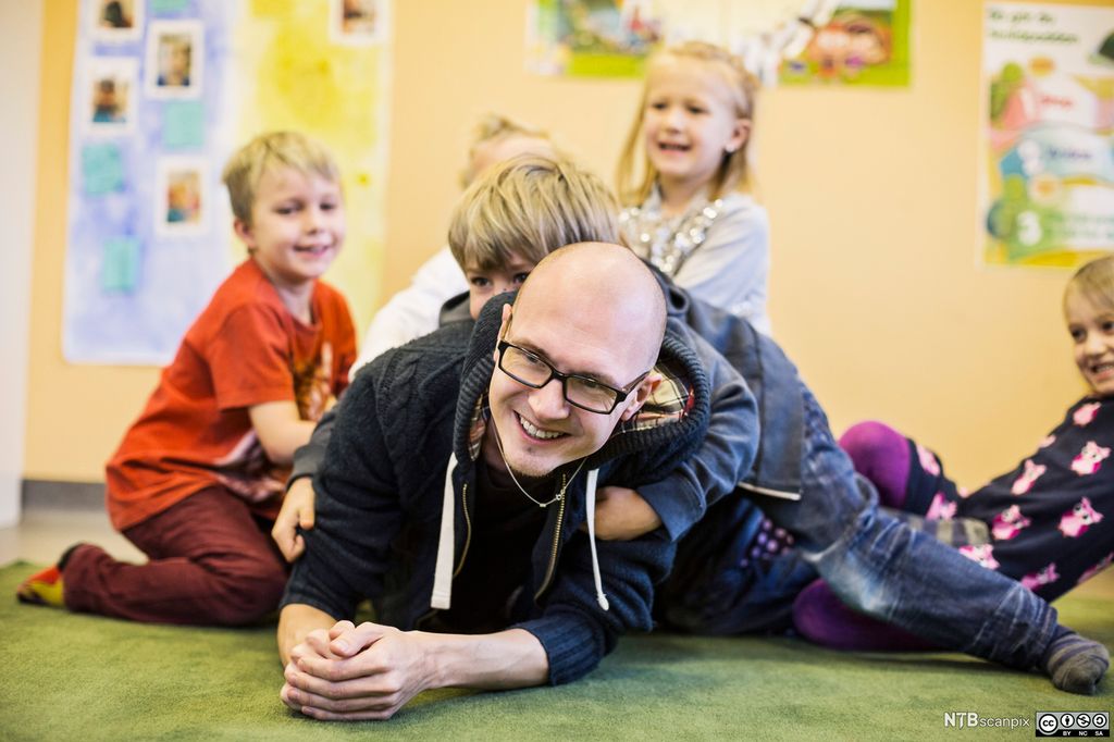 Førskolelærer leker med barn. Foto.