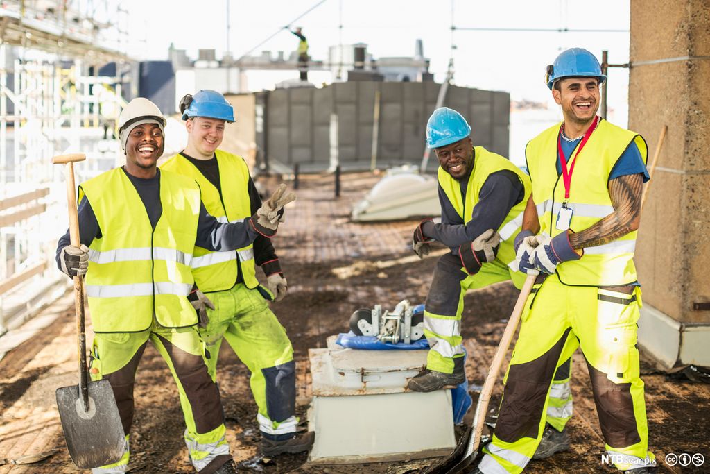 Glade bygningsarbeidere på arbeidsplass. Foto