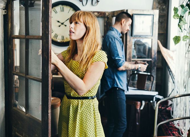 Mann og kvinne ser på retro-møbler i en interiørbutikk. De står med ryggen til hverandre og studere ulike varer. Foto.