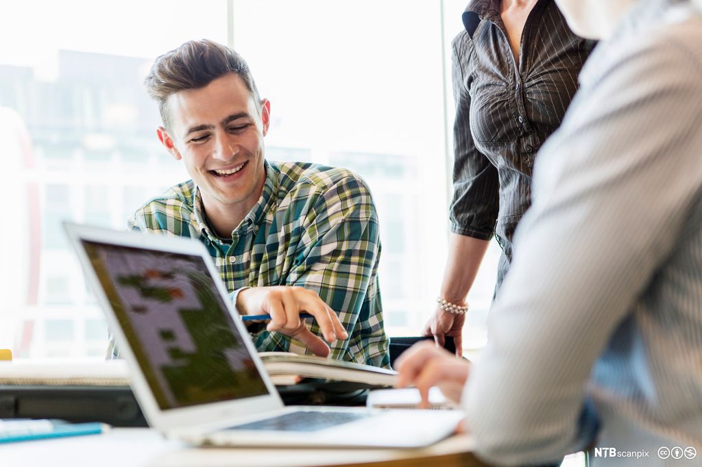 En IT-fagarbeider hjelper en bruker. Foto.