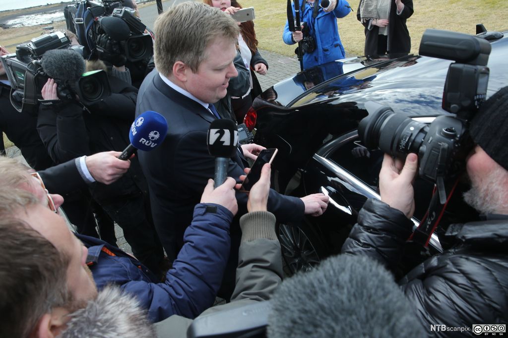 Den islandske statsministeren Sigmundur Davíð Gunnlaugsson omgitt av pressefolk mens han prøver å gå inn i en svart bil. Foto.