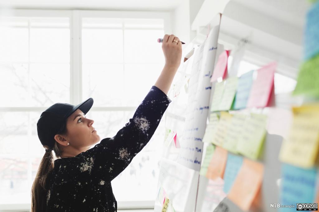 Forretningsutvikler skriver på whiteboard-tavle. Foto.