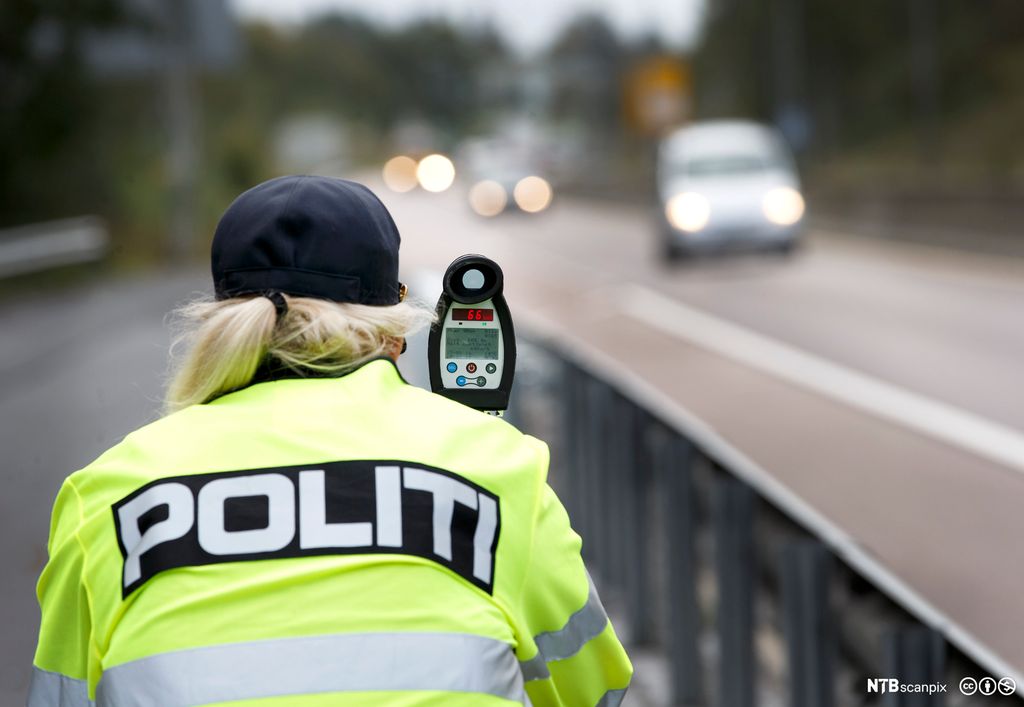 Bilde av en politimann som utfører trafikkontroll med lasermåler.