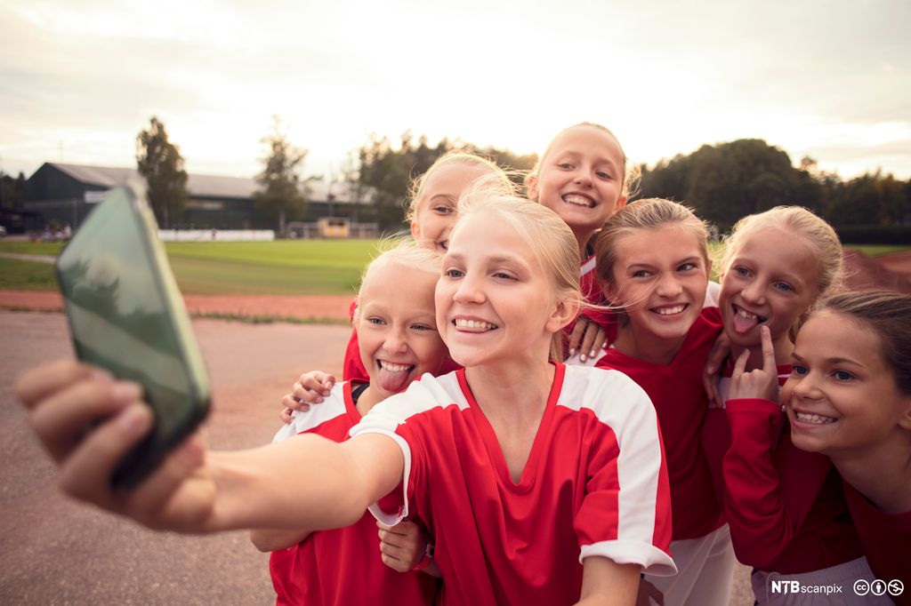 Blide små fotballjenter tar en selfie sammen. Foto.