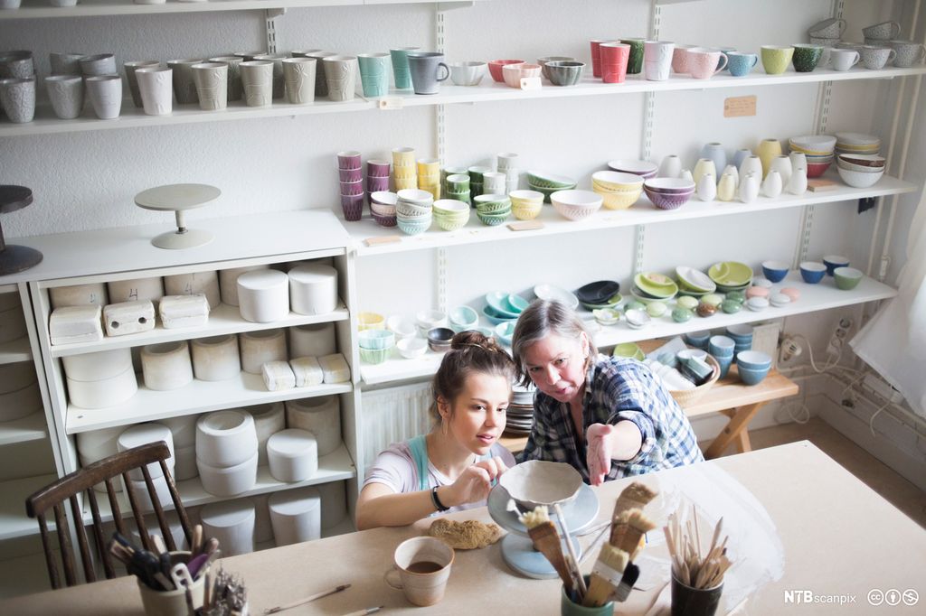 To keramikere ser på keramikk. Foto.