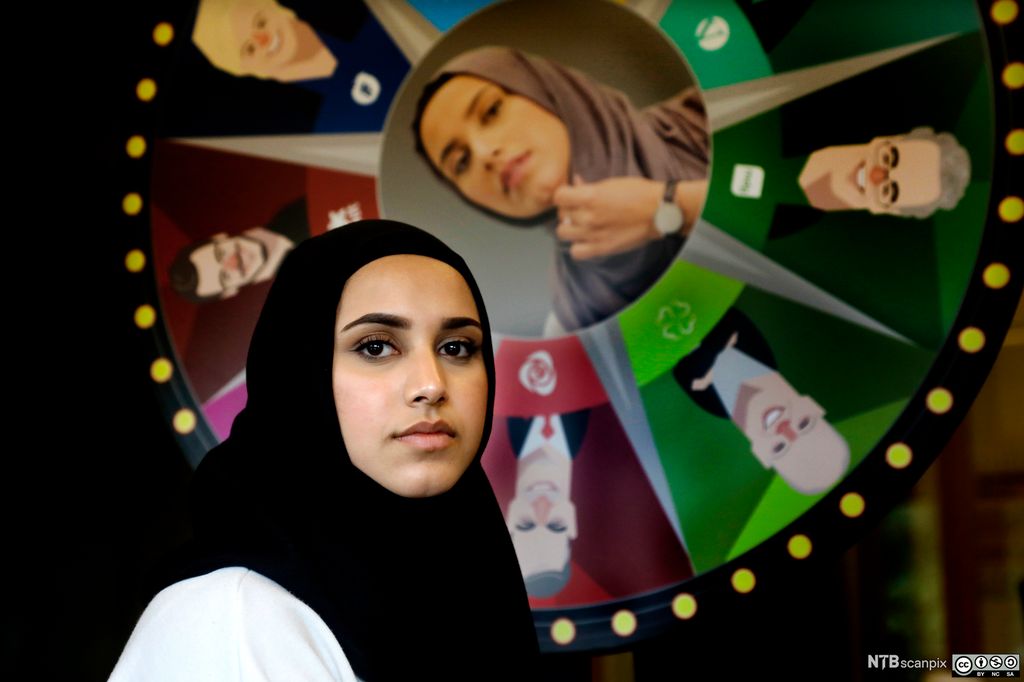 Faten Mahdi Al-Hussaini foran et lykkehjul med bilder av norske politikere. Foto