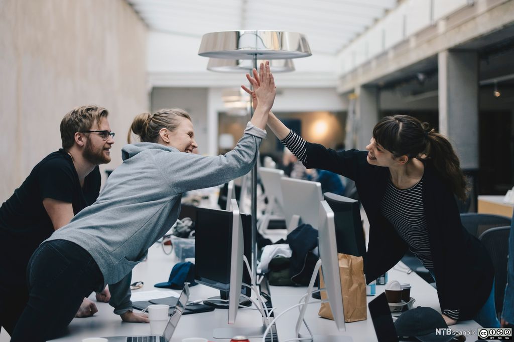 To kollegaer gir hverandre high five. Foto.