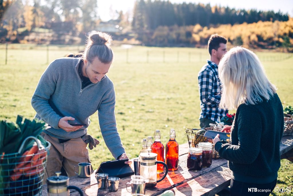 Vareutsalg på bondegård. Bonde og kunde. Foto.