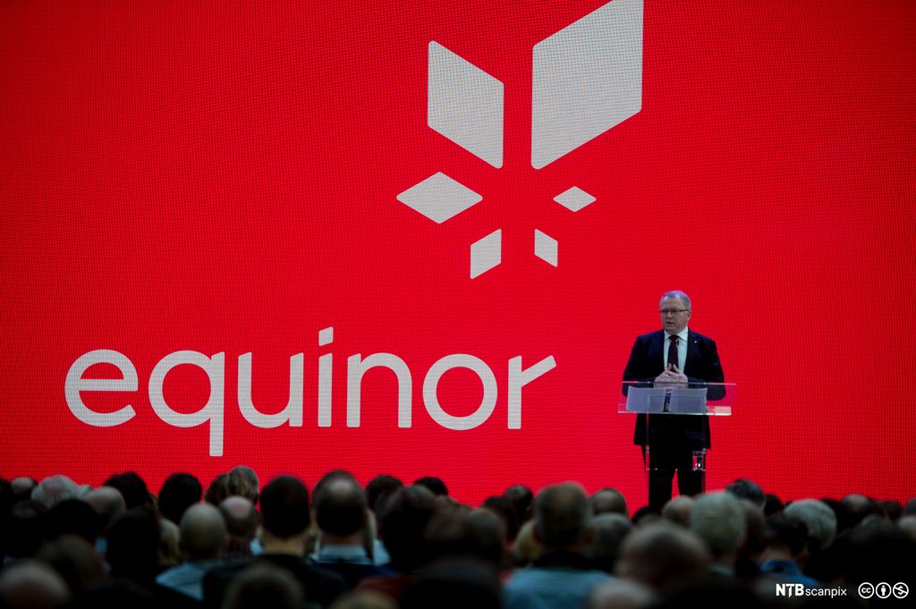 Konsernsjef Eldar Sætre på en scene for å presentere det nye navnet til Statoil – Equinor. Veggen bak han er rød med hvit Equinor-logo på. Foto.