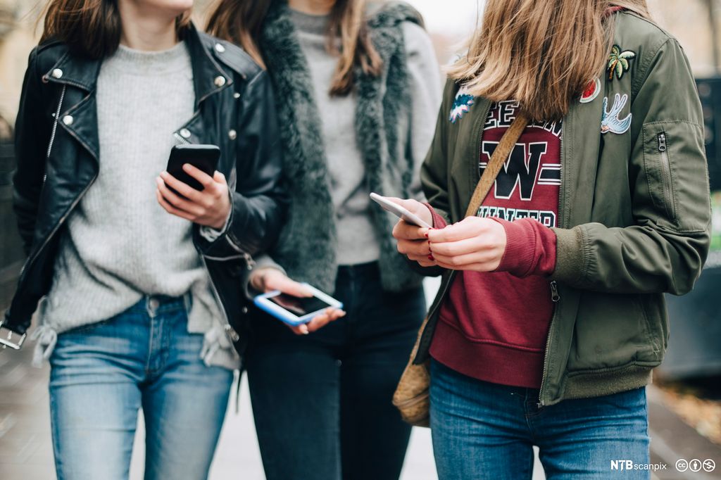 Ungdom med mobiltelefoner i hendene. Foto.