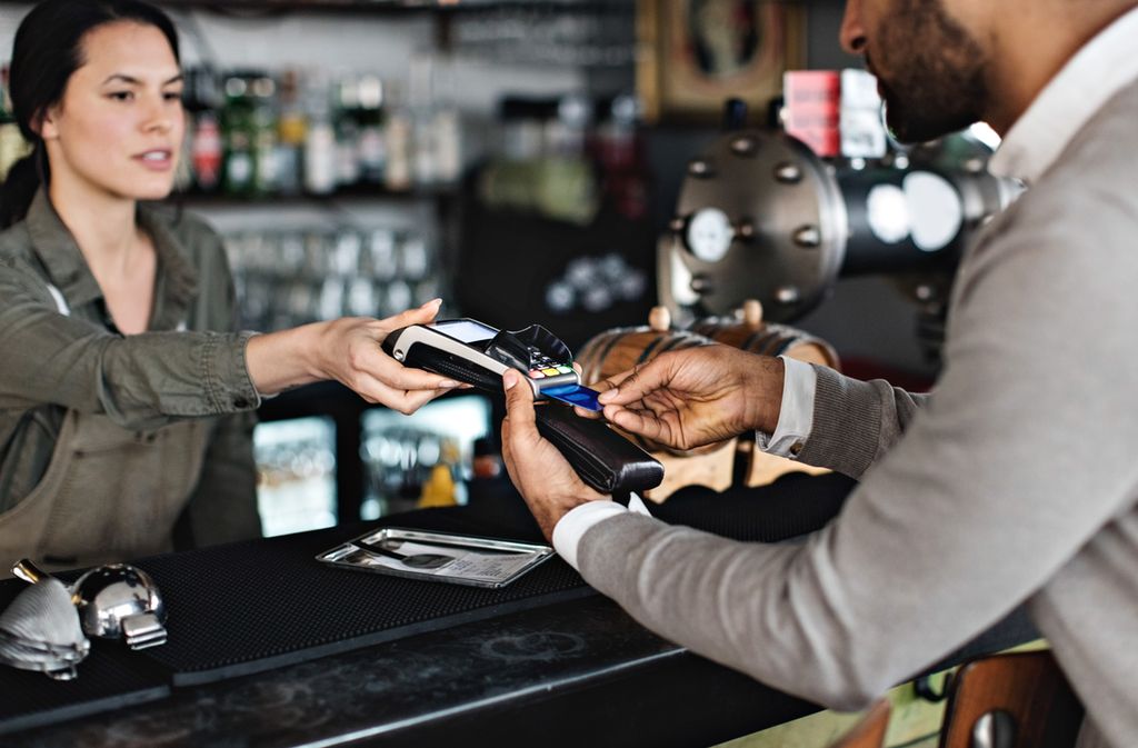 Ei kvinne tek imot betaling frå ein mann som betaler med bankkort. Foto.