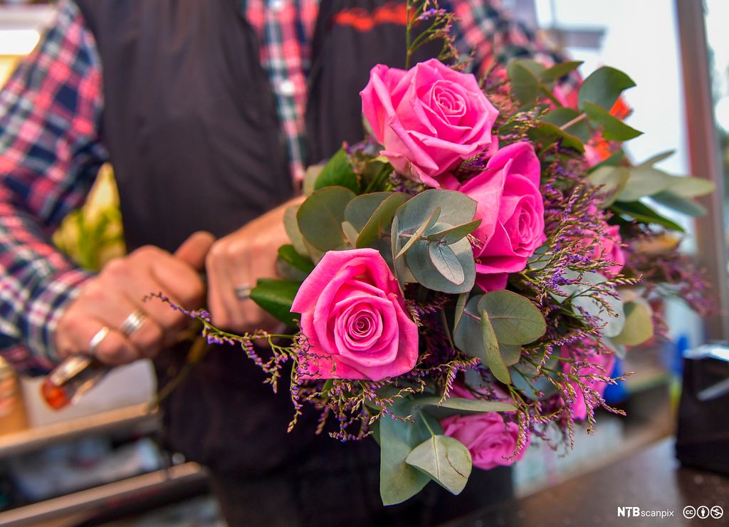 En blomsterdekoratør setter sammen en bukett. Foto.