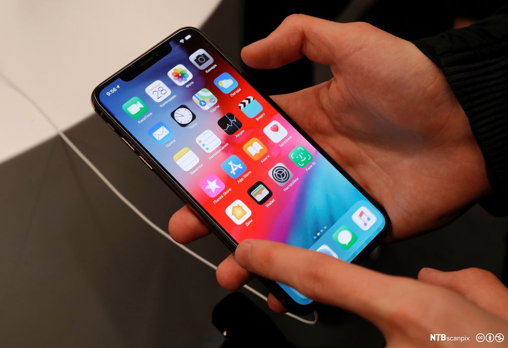 Hender som held ein smarttelefon med ulike appar. Foto.