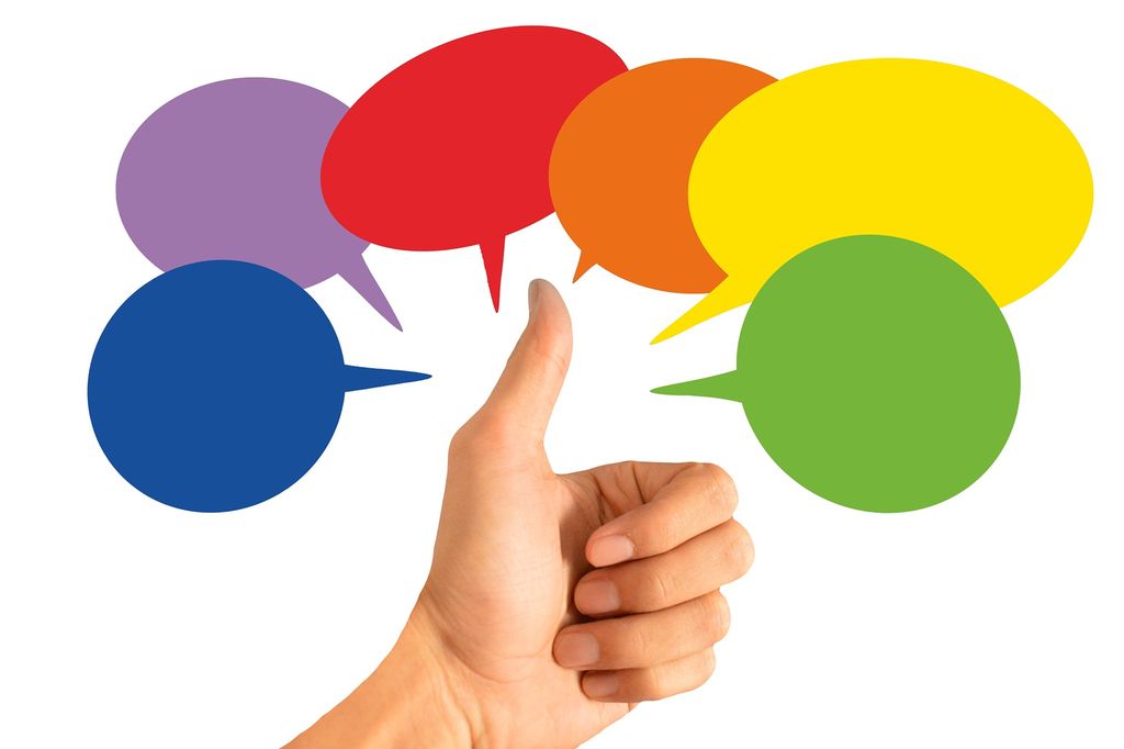 A hand giving a thumbs up, surrounded by colorful speech bubbles. Photo.