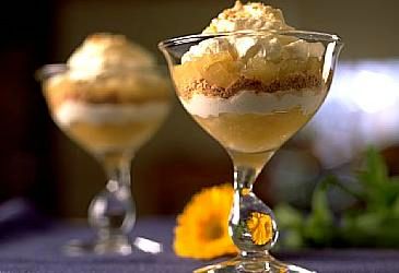 Tilslørte bondepiker i et gjennomsiktig dessertglass med stett. Eplemos, kavring og krem ligger lagvis. Foto.