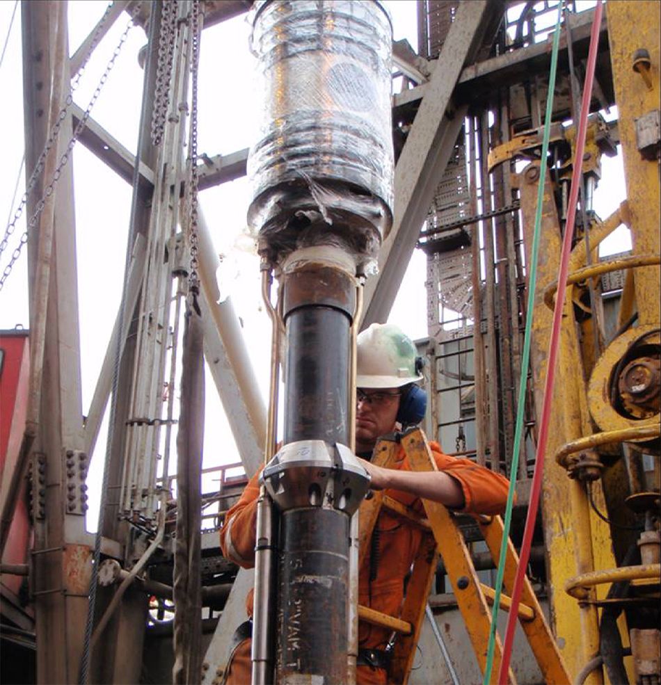 En oljearbeider i oransje arbeidsklær klargjør en tubing hanger for installasjon. Foto.