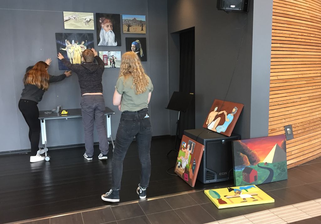 Elevar samarbeider om å henge opp lerret med motiv inspirerte av renessansen. Foto.