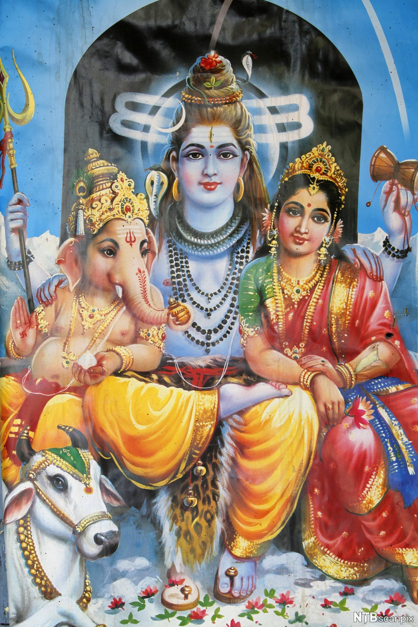 Tre sittande skikkelsar. Skikkelsen i midten er størst. Til venstre er ein skikkelse med elefanthovud og til høgre ein kvinneskikkelse. Begge lener seg mot den som sit i midten. Alle er rikt utsmykka og held ulike gjenstandar. Til dømes held skikkelsen i midten ein trefork og ei lita tromme. Illustrasjon.