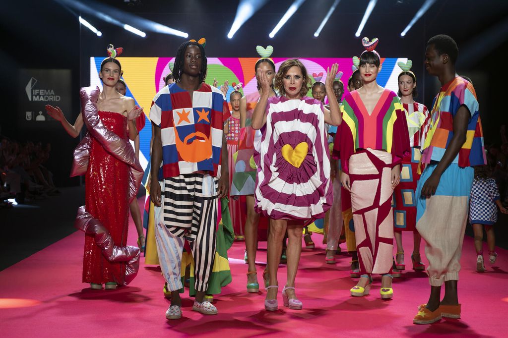 Flere modeller i fargerike klær på en catwalk. Foto.