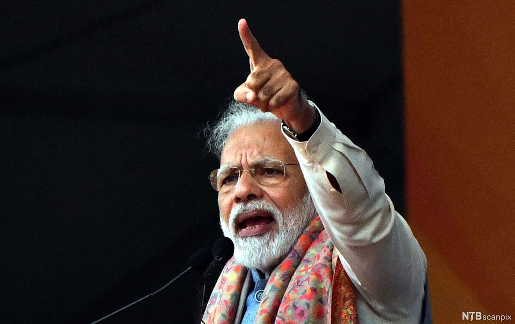 Eldre mann holder tale og peker opp i lufta. Foto.