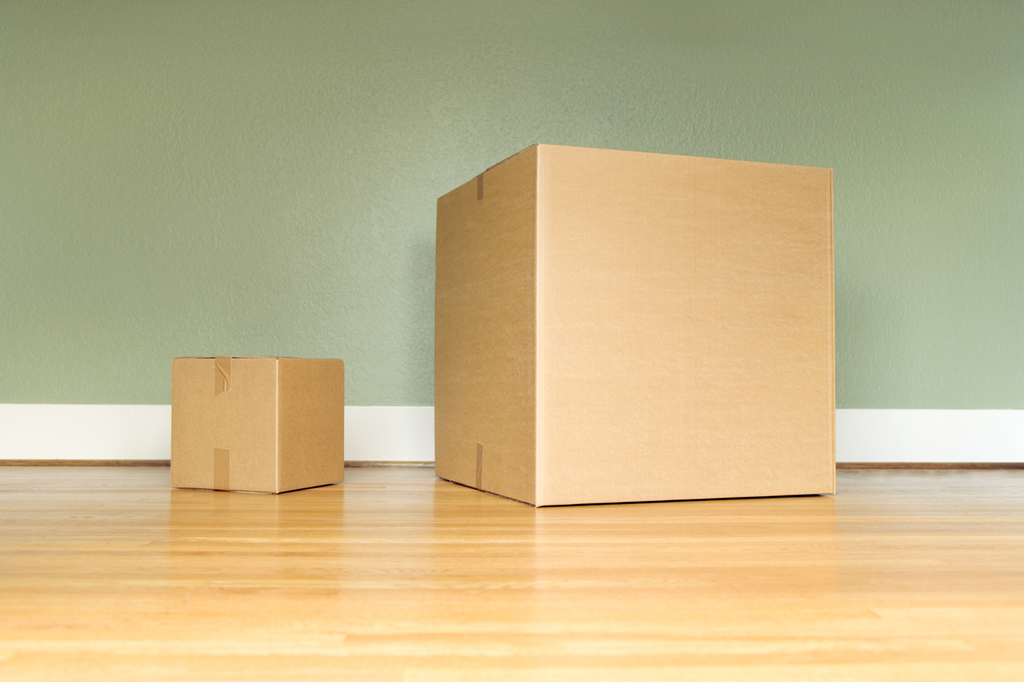 To pappesker med lukket lokk som står ved siden av hverandre på gulvet. Den ene er fire ganger så stor som den andre. Foto.