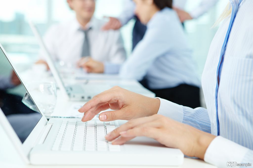 En person skriver på et tastatur i et kontormiljø. Foto.