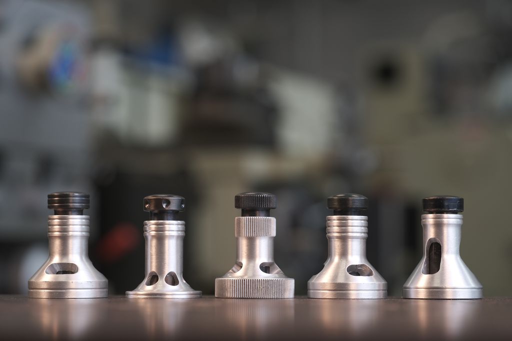 Fem sølvfarga sirkulære verktøy på et bord. Foto.