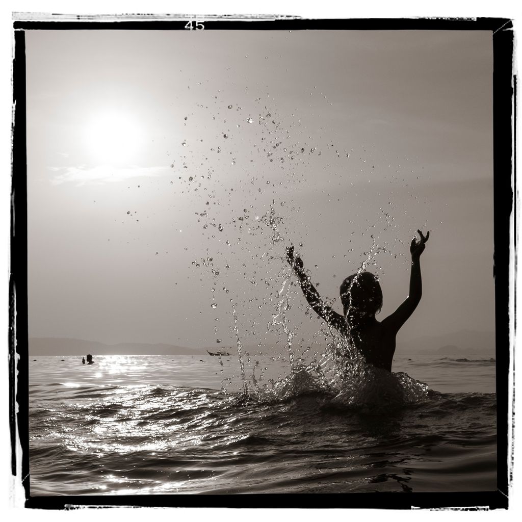 Silhuett av en person som spruter vann opp i lufta. Foto.