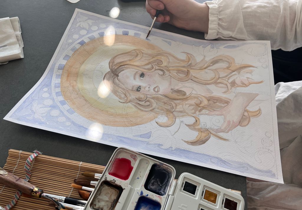 Ei hånd maler et art nouveau-inspirert bilde med akvarell. Foto.