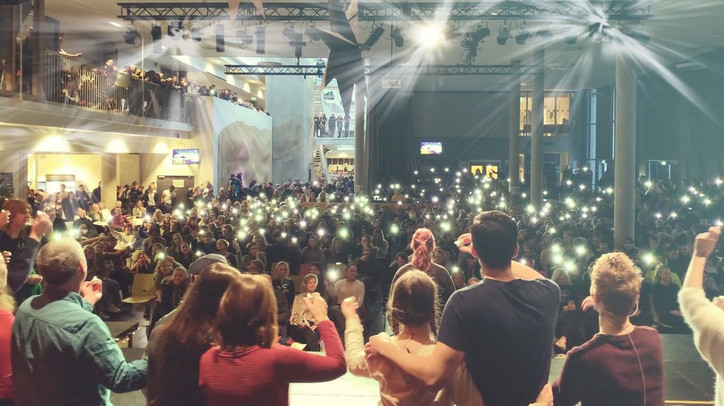 Elever og lærere står med tente lys. 