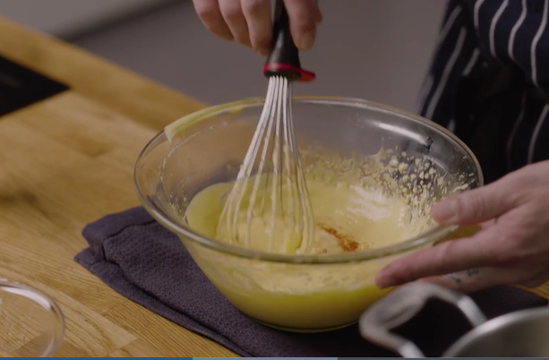 En hollandés blir pisket i en glassbolle. Et kjøkkenhåndkle ligger under bollen. Foto.