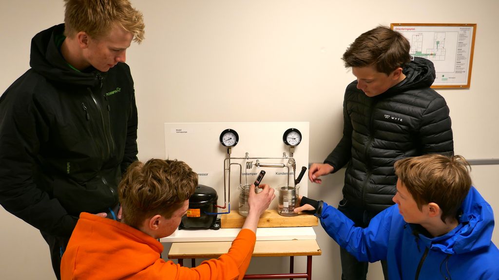 Fire gutter undersøker en varmepumpemodell. Foto.