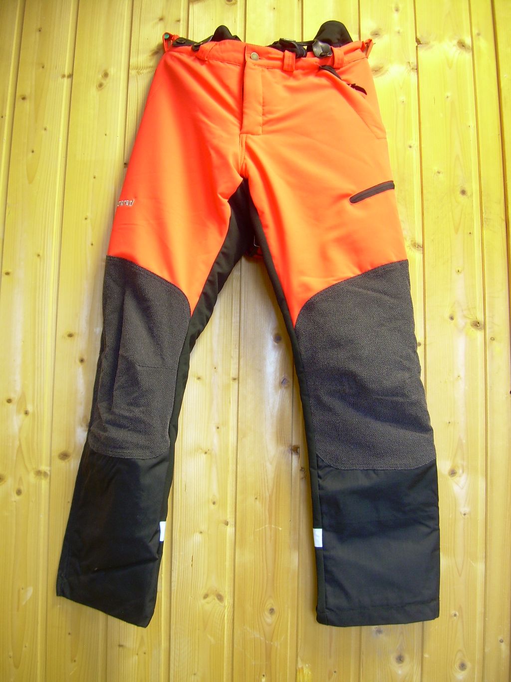 Oransje og svart vernebukse. Foto.