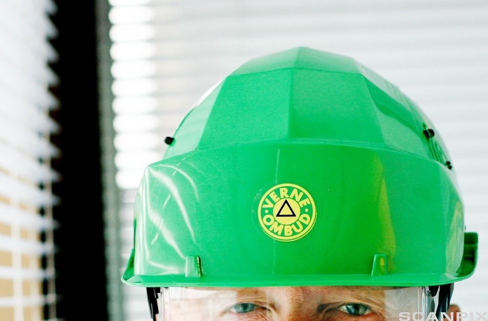 Mann med grønn vernehjelm med teksten verneombud. Foto.