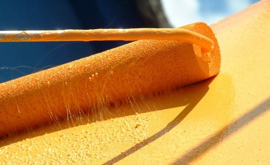 Rull med gul maling på. Foto.