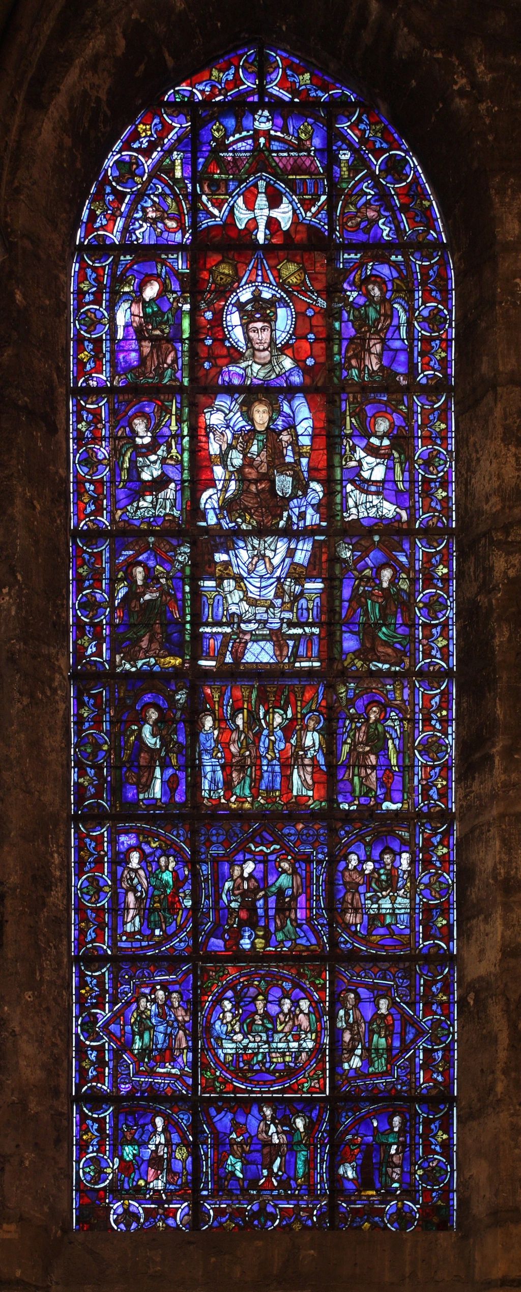 Et glassmaleri der hovedmotivet er jomfru Maria, Jesus og Den hellige ånd i form av en due, Den nedre delen skildrer Kristi fristelse. Foto.